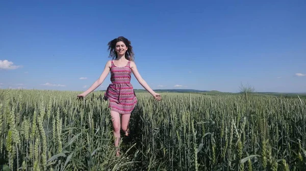 Beauty girl running on green wheat field. Freedom concept. Happy woman outdoors. Harvest