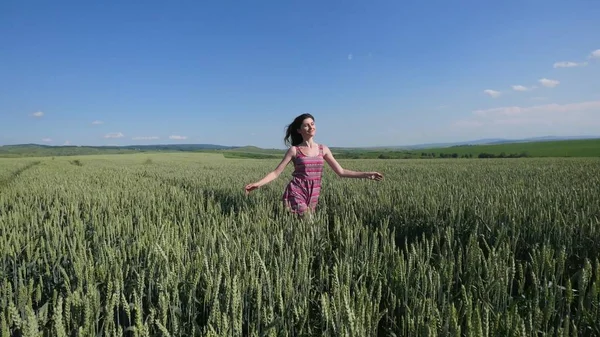 Beauty girl running on green wheat field. Freedom concept. Happy woman outdoors
