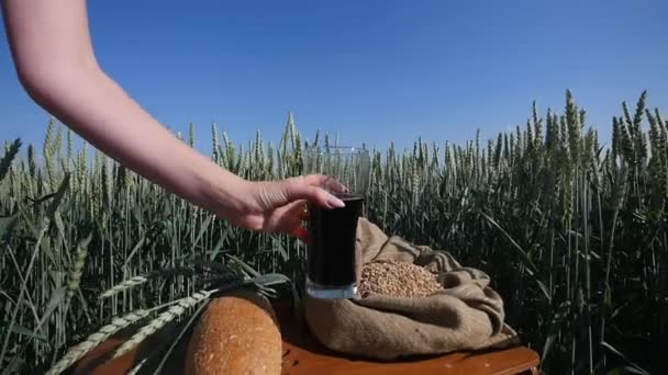 Mujeres mano tomando un vaso de kvass sobre el fondo de trigo — Vídeos de Stock