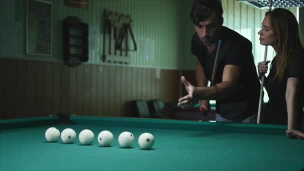 Man visar hans tjej var att slå bollen - ung kvinna som fick råd på skytte poolen bollen medan du spelar Biljard — Stockvideo