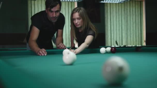 Ο άνθρωπος που δείχνει το κορίτσι του πού να χτυπήσει την μπάλα - νεαρή γυναίκα που λαμβάνουν συμβουλές για γυρίσματα πισίνα μπάλα ενώ παίζετε μπιλιάρδο — Αρχείο Βίντεο