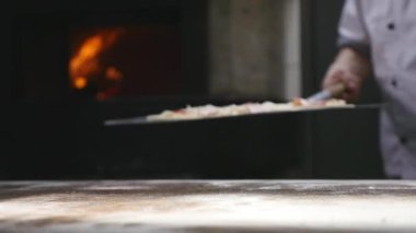Bir şef pizza onun tuğla fırın içine koyar.