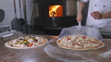 Bir şef pizza onun tuğla fırın içine koyar.