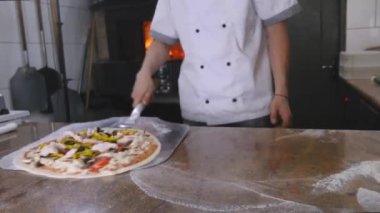 Bir şef pizza onun tuğla fırın içine koyar.