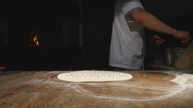 Aşçı mutfakta, pizzanın malzemelerini koyuyor. Pizza konsepti. Gıda üretimi ve teslimatı