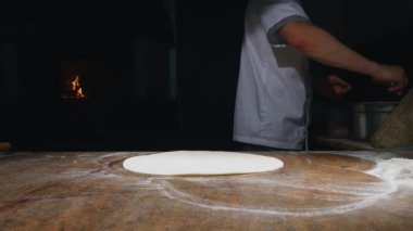 Aşçı mutfakta, pizzanın malzemelerini koyuyor. Pizza konsepti. Gıda üretimi ve teslimatı