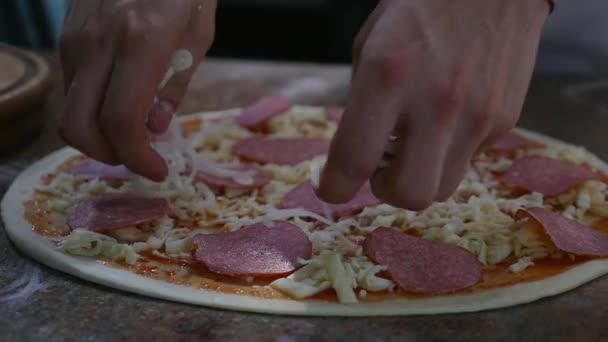 Cocina las manos en la cocina poniendo los ingredientes en la pizza. Concepto de pizza. Producción y entrega de alimentos — Vídeos de Stock