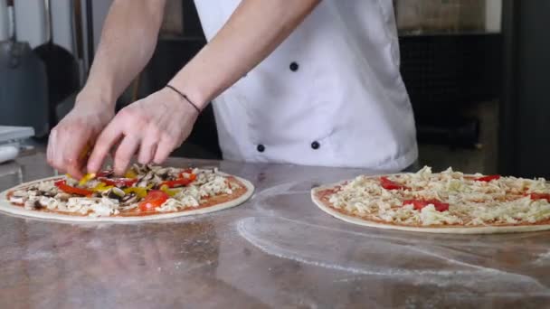 Cocina las manos en la cocina poniendo los ingredientes en la pizza. Concepto de pizza. Producción y entrega de alimentos — Vídeo de stock