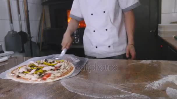 A chef puts a pizza into his brick oven — Stock Video