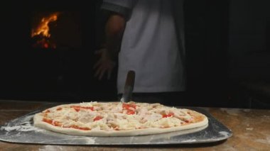 Bir şef pizza onun tuğla fırın içine koyar.