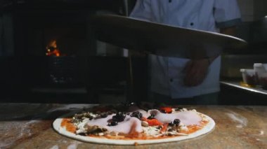 Bir şef pizza onun tuğla fırın içine koyar.