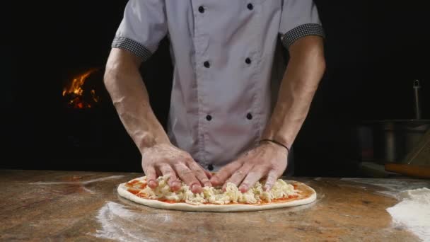 Cocina las manos en la cocina poniendo los ingredientes en la pizza. Concepto de pizza. Producción y entrega de alimentos — Vídeo de stock