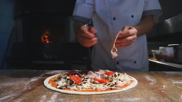 Cuire les mains dans la cuisine en mettant les ingrédients sur la pizza. Concept de pizza. Production et livraison de denrées alimentaires — Video