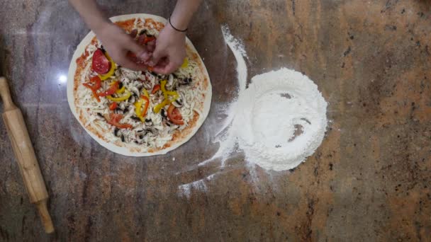 Cocina las manos en la cocina poniendo los ingredientes en la pizza. Concepto de pizza. Producción y entrega de alimentos. Vista superior — Vídeo de stock