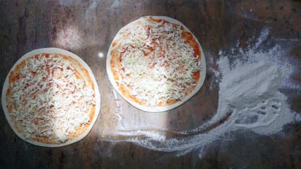 De handen van de koks in de keuken zetten de ingrediënten op de pizza. Pizza concept. Productie en levering van voedsel. Bovenaanzicht — Stockvideo