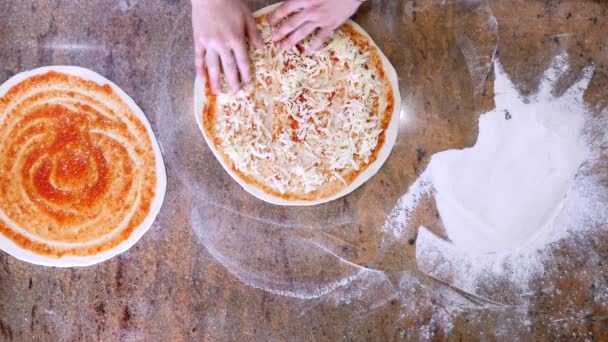 Cocina las manos en la cocina poniendo los ingredientes en la pizza. Concepto de pizza. Producción y entrega de alimentos. Vista superior — Vídeo de stock