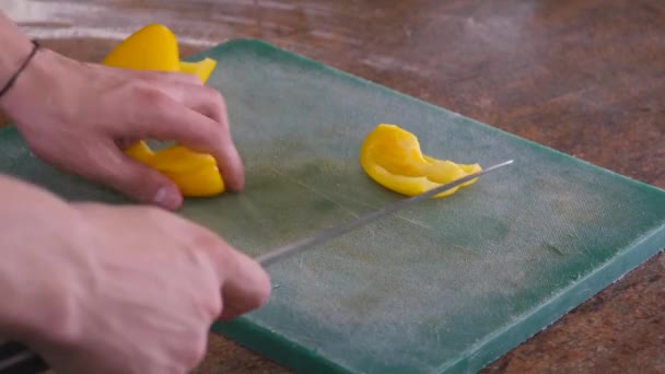 Chef cortando pimentão amarelo com legumes no fundo — Vídeo de Stock