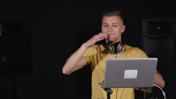 De dj mixen van muziek staan op zijn dek, dans met zijn koptelefoon om zijn nek — Stockvideo