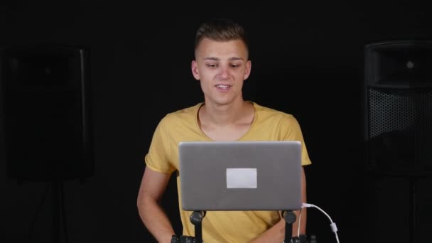 DJ ajusta o equipamento e olha para o laptop — Vídeo de Stock