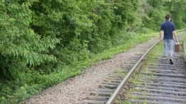 demiryolu hattı bavula olan genç bir adam. Tren kaybetmek büyük bir şehirde, genç bir adam gider büyük şehirde kaybolmak