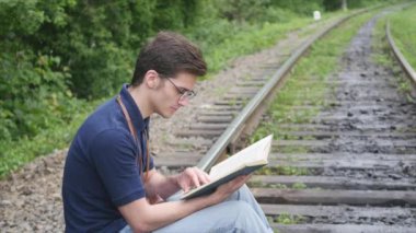 genç adam bir demiryolu parça üzerine bir kitap okuma