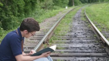 genç adam bir demiryolu parça üzerine bir kitap okuma