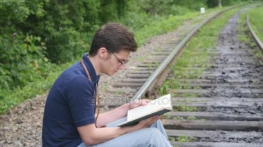 genç adam bir demiryolu parça üzerine bir kitap okuma