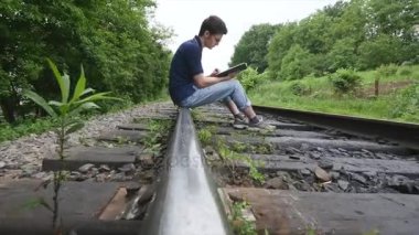 genç adam bir demiryolu parça üzerine bir kitap okuma