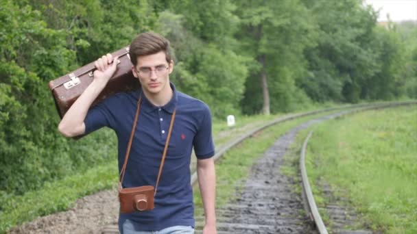 En ung man med en resväska på järnvägslinjen. Tåg förlora i en storstad, en ung man går till vilse i den stora staden — Stockvideo