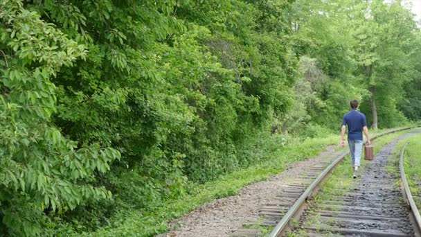Mladý muž s kufrem na železniční trati. Vlak ztratí ve velkém městě, mladý muž jde ztratit se ve velkoměstě — Stock video