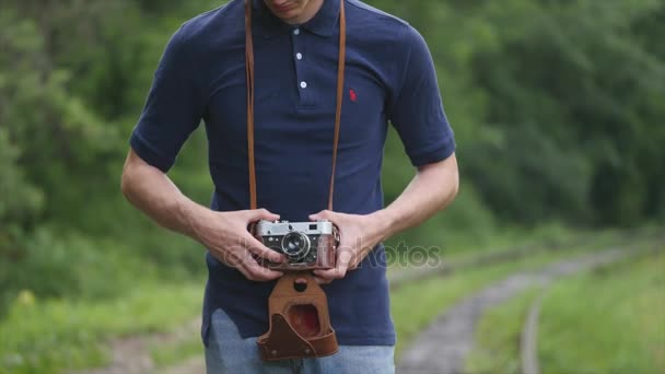 Mannen fotografen innehar en vintage kamera på en bakgrund spår — Stockvideo