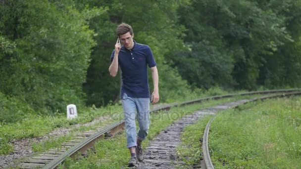 Ένας νεαρός άνδρας σε μια σιδηροδρομική γραμμή — Αρχείο Βίντεο
