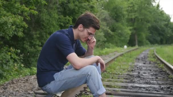 Junger Mann telefoniert auf Bahngleis — Stockvideo