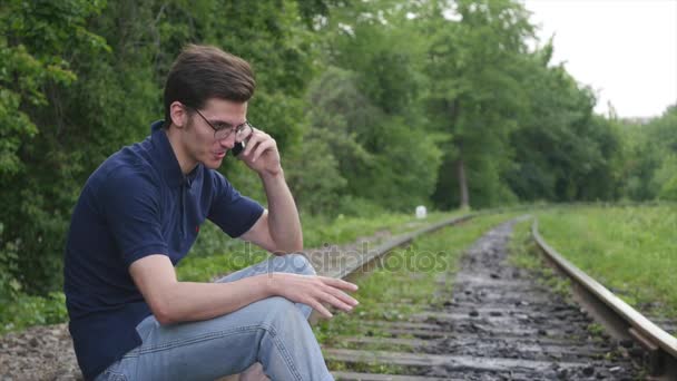Jeune homme parle par téléphone sur une voie ferrée — Video