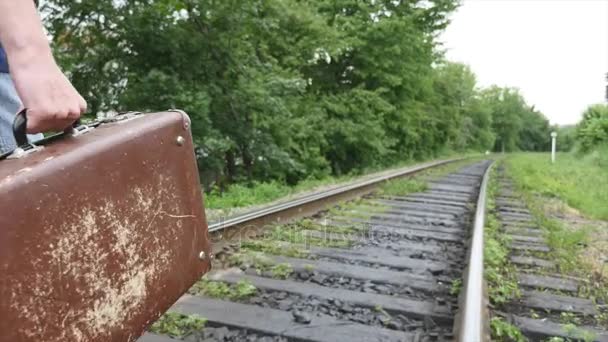 Die Hand eines Mannes mit Koffer, der auf Bahngleisen läuft — Stockvideo