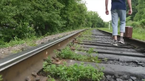 The hand of man with suitcase walking on railway track — Stock Video
