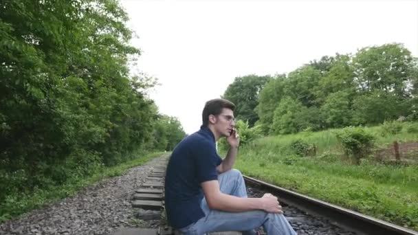 Jovem fala por telefone em uma linha férrea — Vídeo de Stock