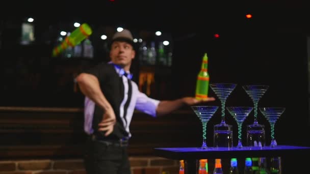 Akrobatisk show utförs av bartendern jonglera två flaskor. bar bakgrund. slowmotion. selektivt fokus — Stockvideo