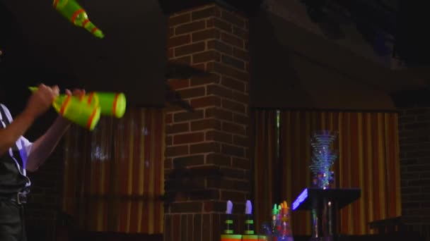 Акробатическое шоу в исполнении бармена, жонглирующего четырьмя бутылками. close up — стоковое видео