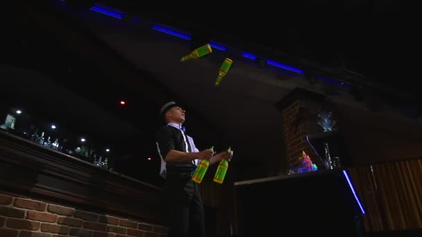 Akrobatische Show von Barkeeper, der mit vier Flaschen jongliert. Zeitlupe. von unten — Stockvideo