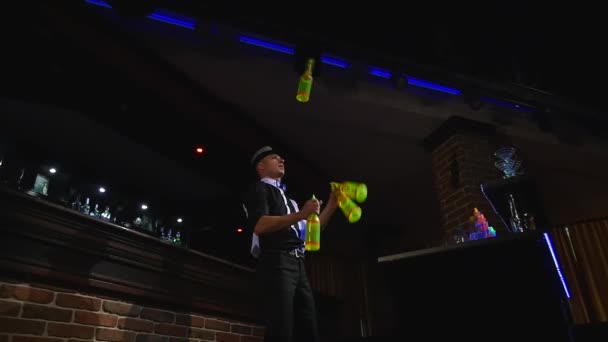 Akrobatické představení barmanem žonglování čtyři láhve. Zpomalený pohyb. pohled zdola — Stock video
