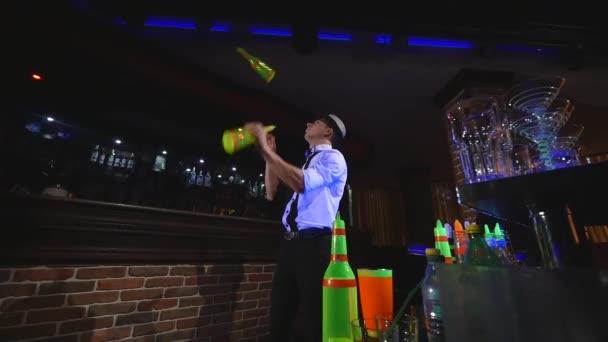 Acrobatische show uitgevoerd door barman jongleren twee flessen. Bar achtergrond — Stockvideo