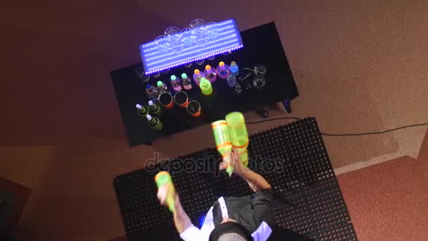 Акробатическое шоу в исполнении бармена, жонглирующего тремя бутылками. Замедление. вид сверху — стоковое видео