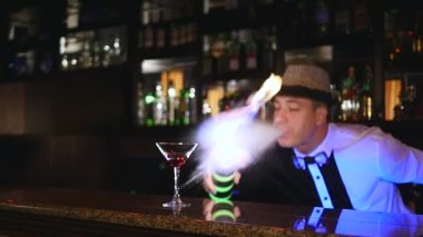 Genç, çekici profesyonel barmen, serin, profesyonel, inanılmaz hileler iki şişe ile yapma barmen dirsek, kusmaya yakalamak barın arkasında duran gösteri yangın