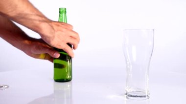 Bir şişe bira beyaz bir arka plan üzerinde bir bardağa dökülür