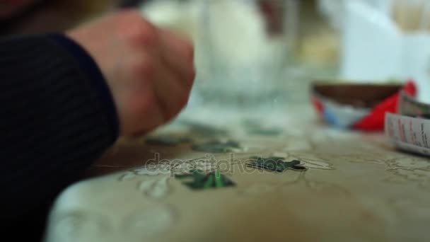 가까이: 프레임에서는 밝은 갈색 테이블에 유명한 만화 캐릭터와 함께 퍼즐을 하 고 작은 아이 손에 — 비디오