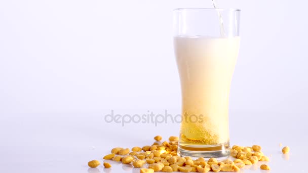 Birra è versando in vetro su sfondo bianco con arachidi sottaceto — Video Stock