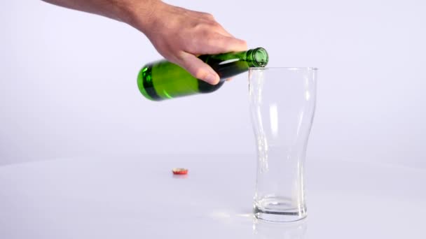 Eine Flasche Bier wird in eine Tasse auf weißem Hintergrund gegossen — Stockvideo