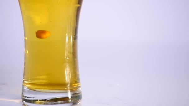 Sklenice piva s maticí vyprazdňování na bílém pozadí. Detailní záběr