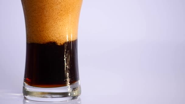 Темне пиво наливається в склянку на білому тлі. крупним планом — стокове відео